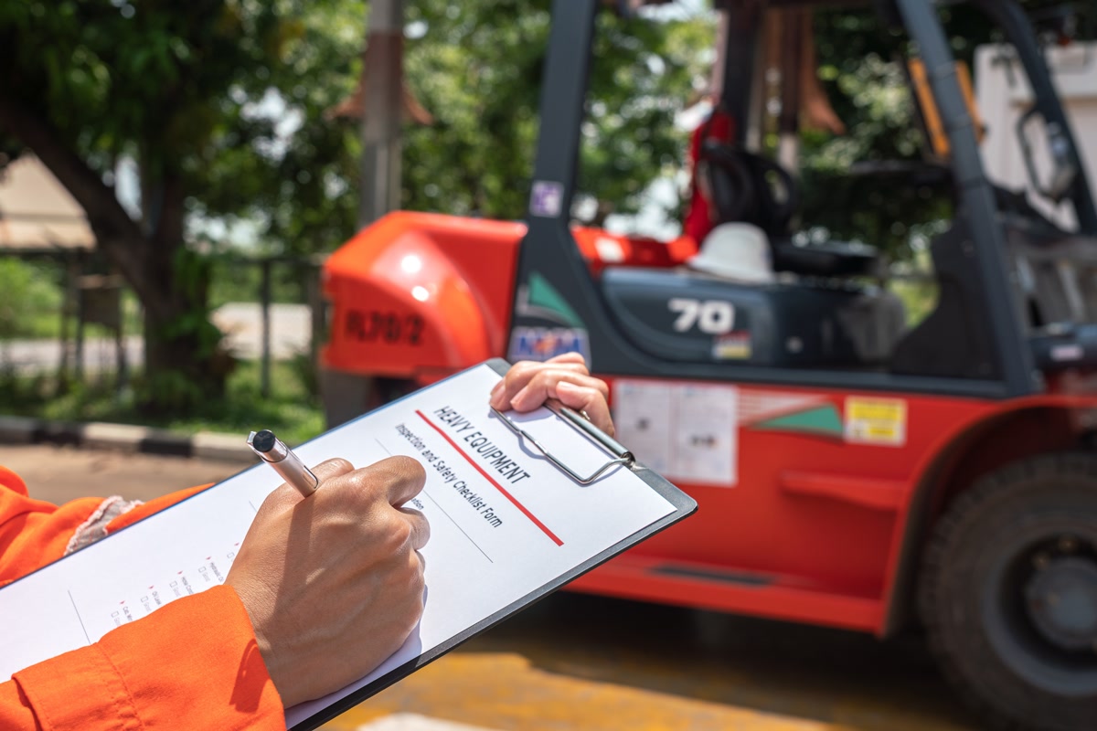 An inspector working through an equipment checklist beside a machine