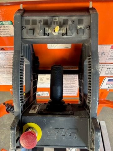Platform control box on the JLG 1930ES with the drive joystick, function switches, and red stop button