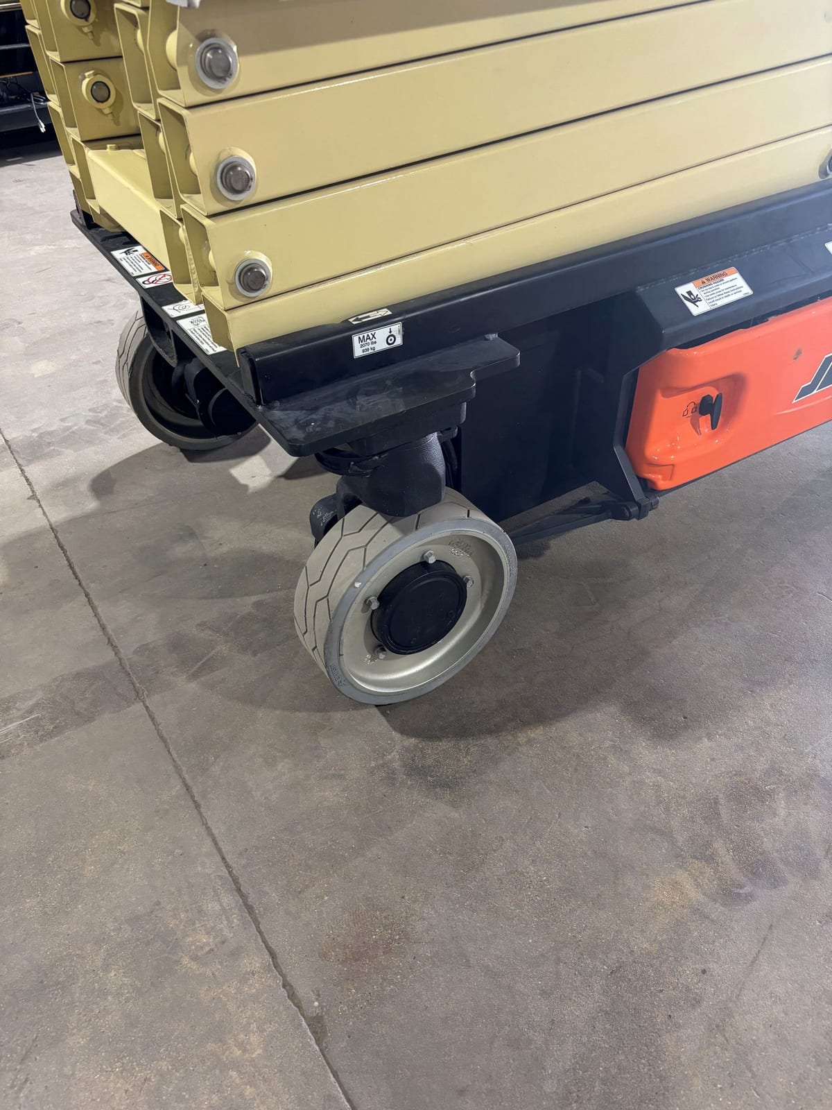 Gray non-marking tire on a rear corner of the JLG 3246ES below the scissor stack