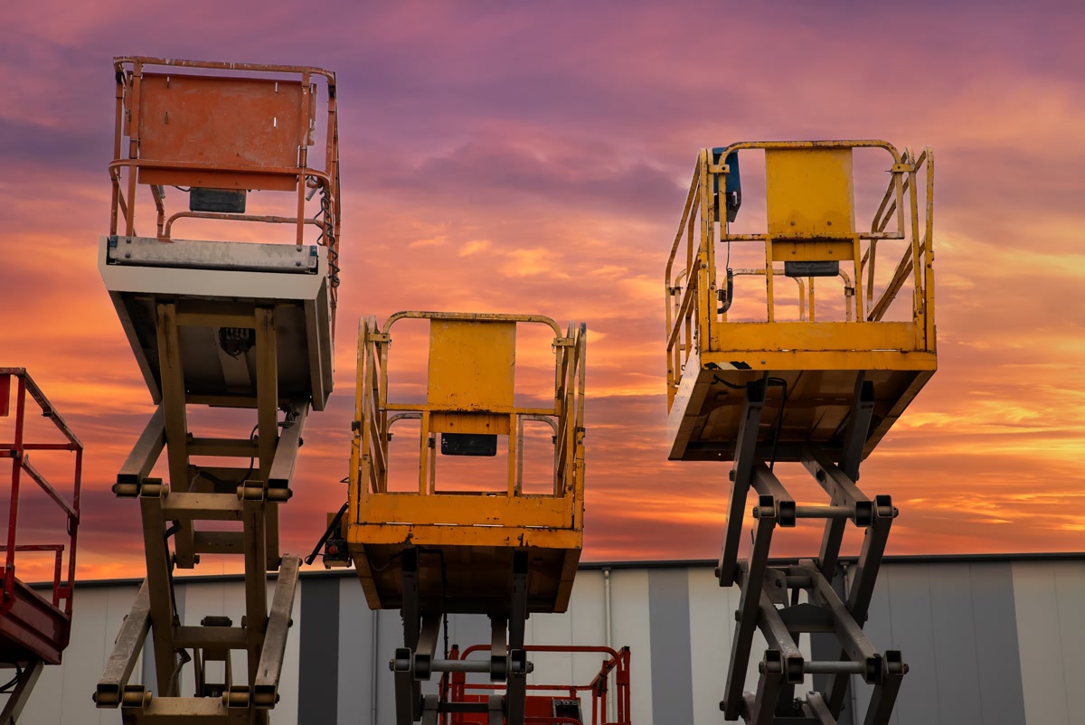 Scissor lift platforms raised against a sunset sky