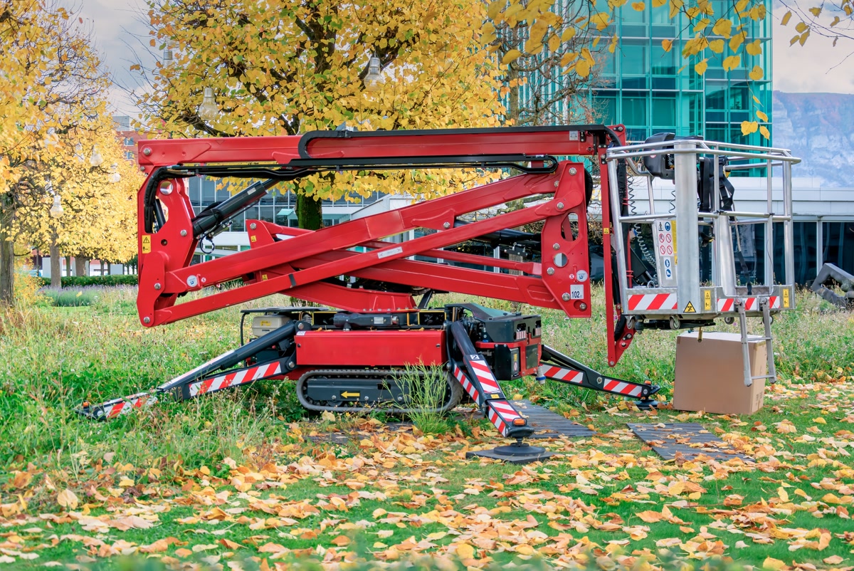 A tracked spider lift with outriggers set on grass