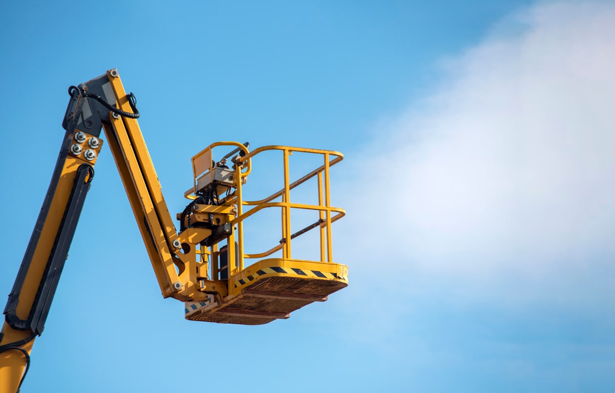 An articulating boom lift raised against a clear sky
