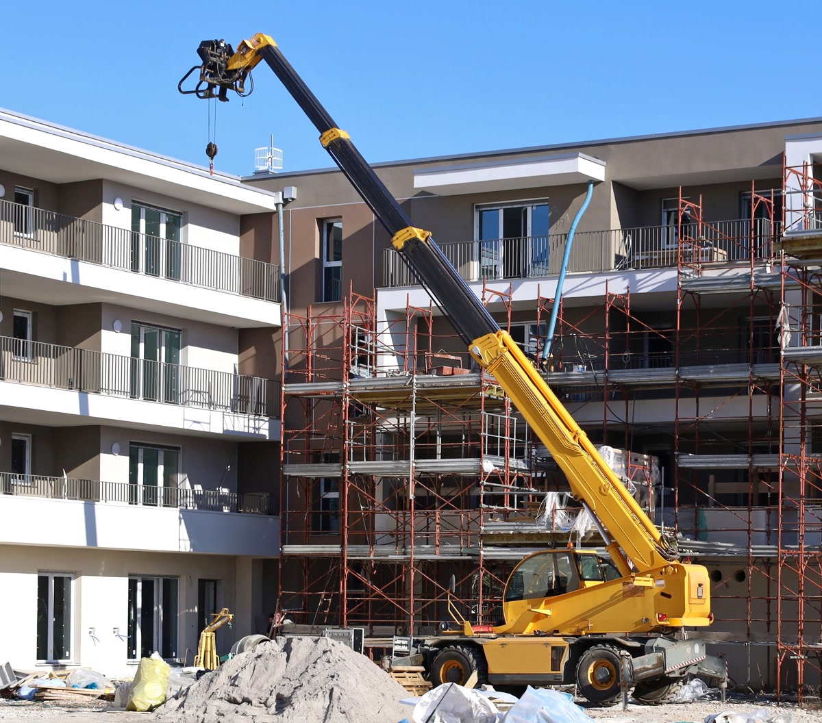 A yellow telehandler with its boom raised at a building site